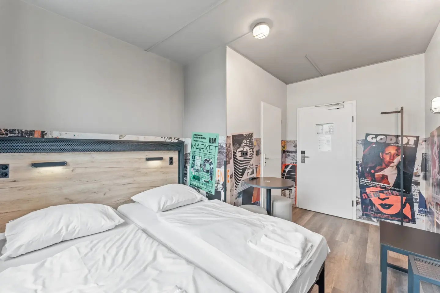 Klassenfahrt Berlin - Doppelbett mit weißer Bettwäsche in Raum mit bunten Wänden