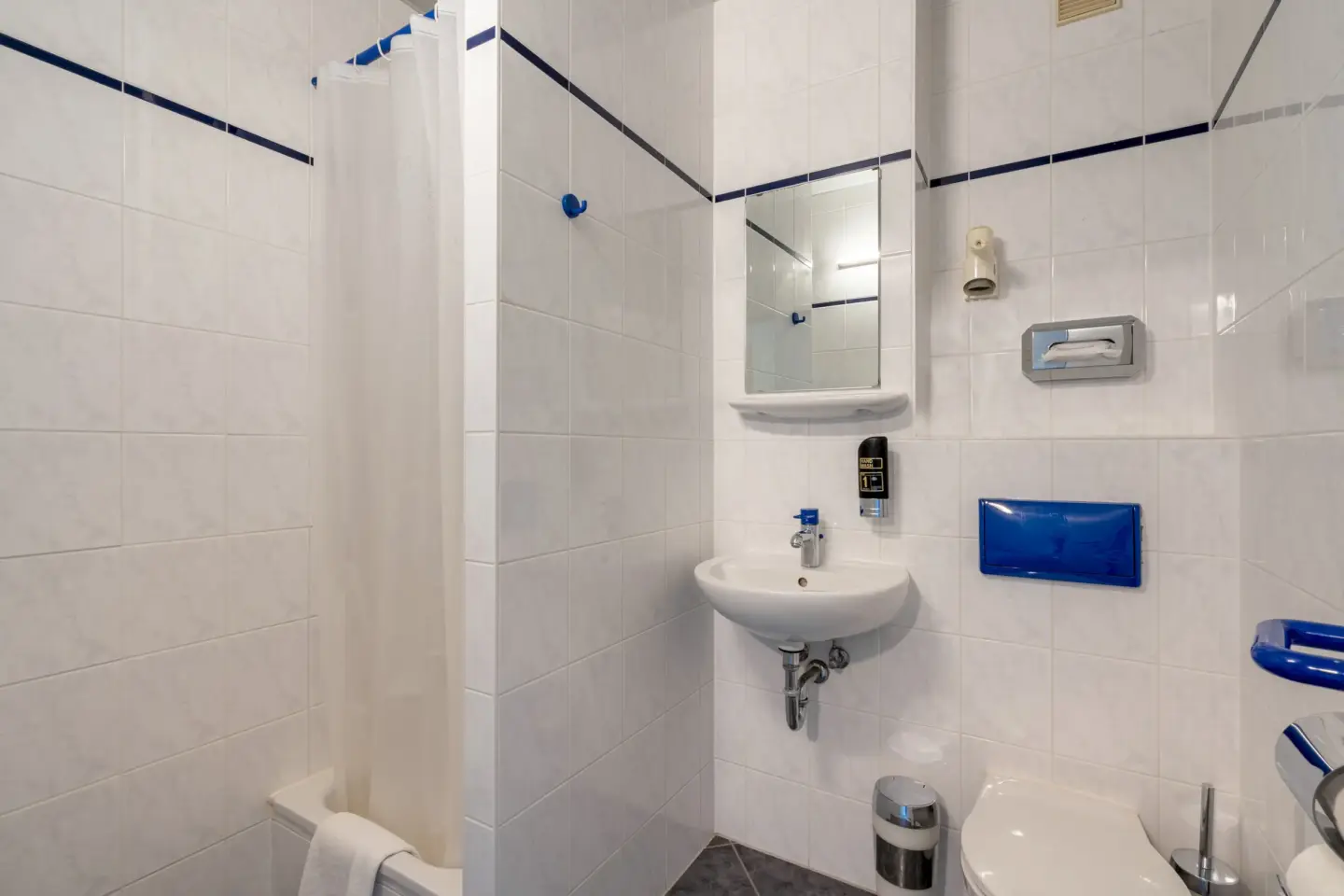 Klassenfahrt Berlin - Badezimmer mit hellen Fliesen, Dusche, Waschbecken und WC