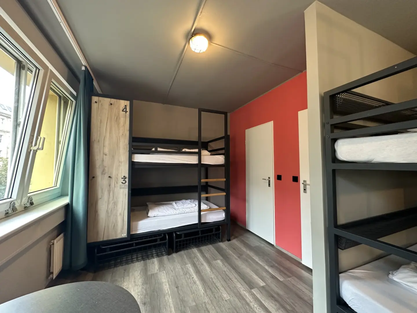 Klassenfahrt Berlin - ein Doppelstockbett steht zwischen einem Fenster und einer roten Wand