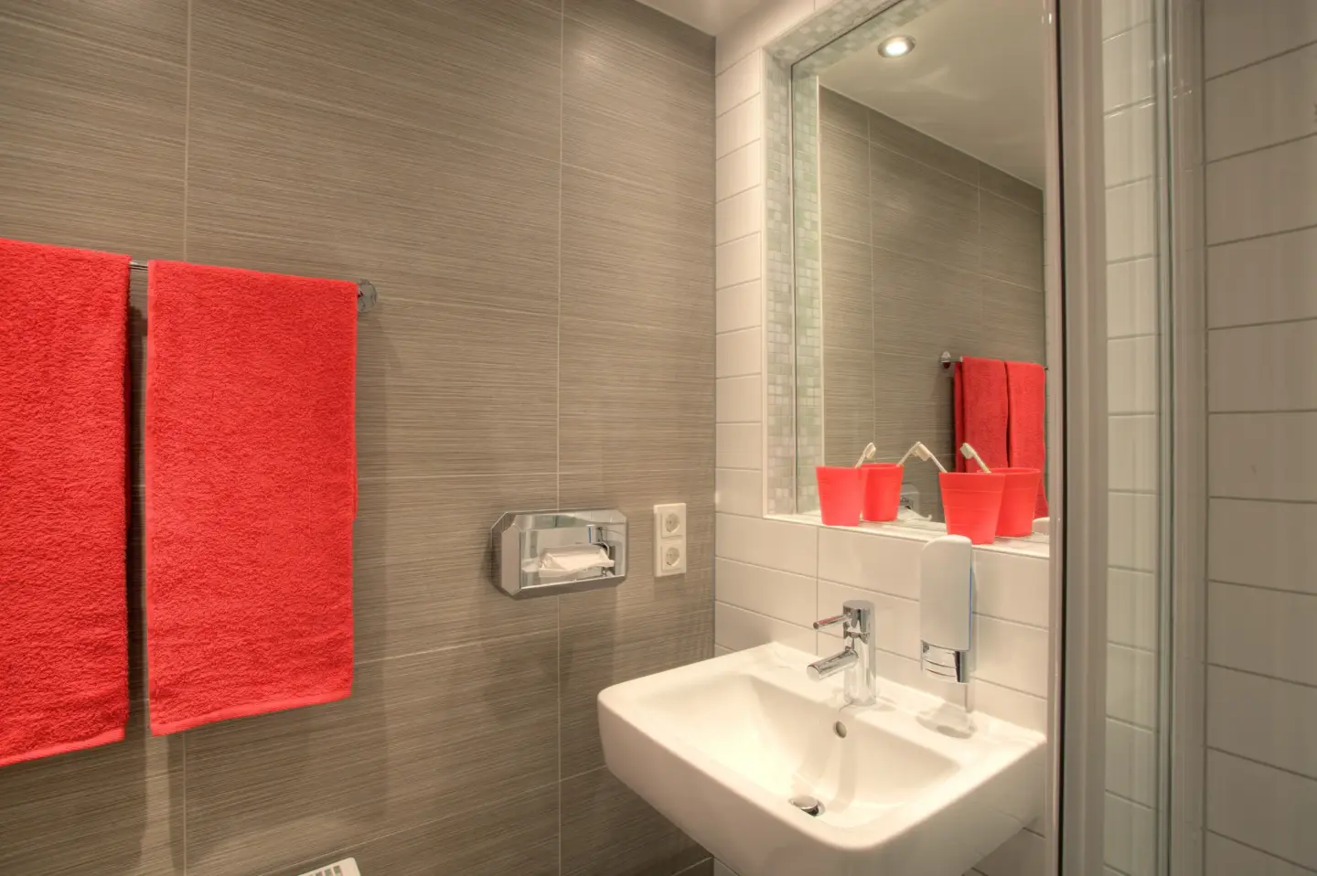 Klassenfahrt Berlin - Badezimmer mit Waschbecken, roten Handtüchern und roten Zahnputzbechern