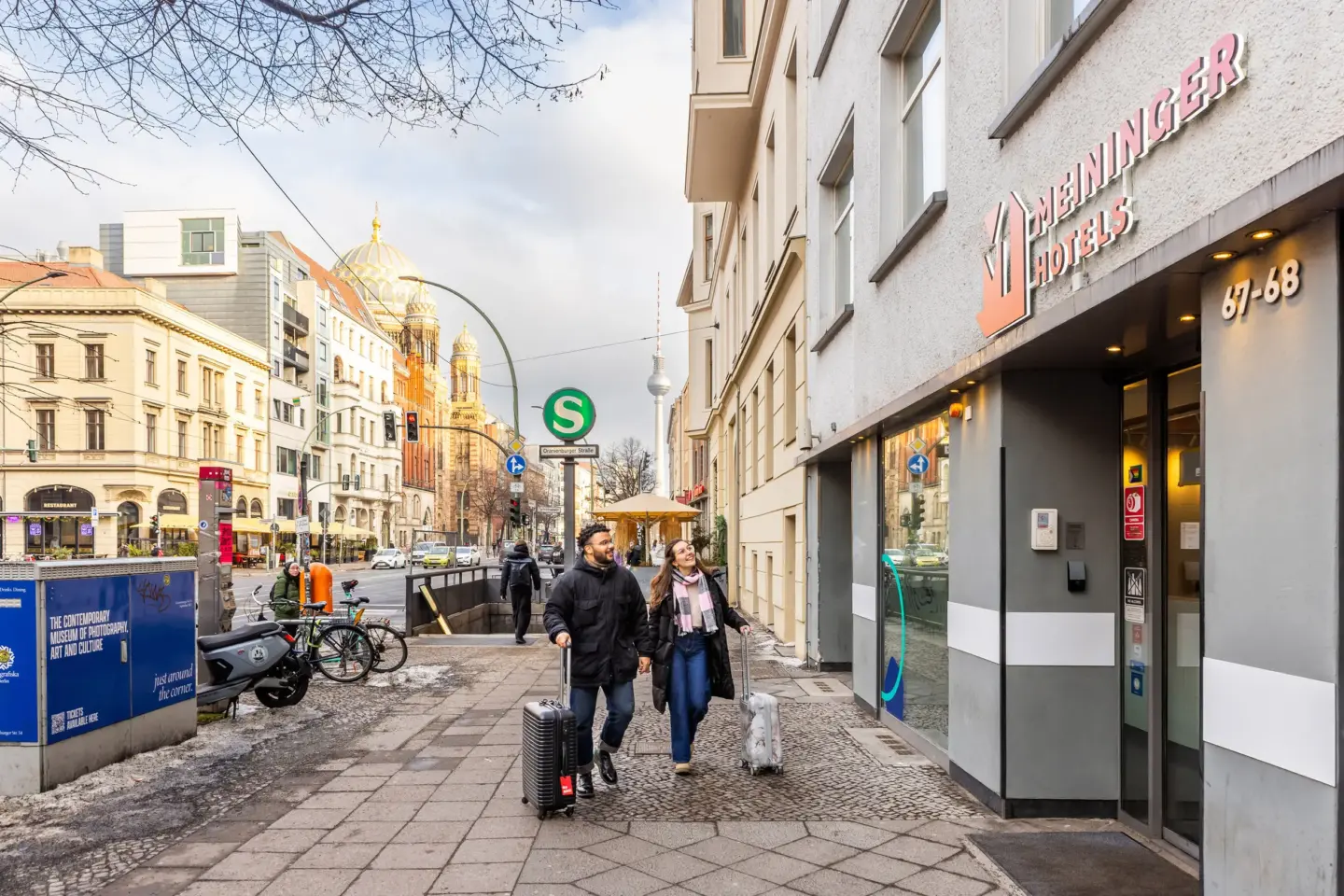Klassenfahrt Berlin - Mann und Frau mit Koffer vor Eingang des Meininger Humboldthaus