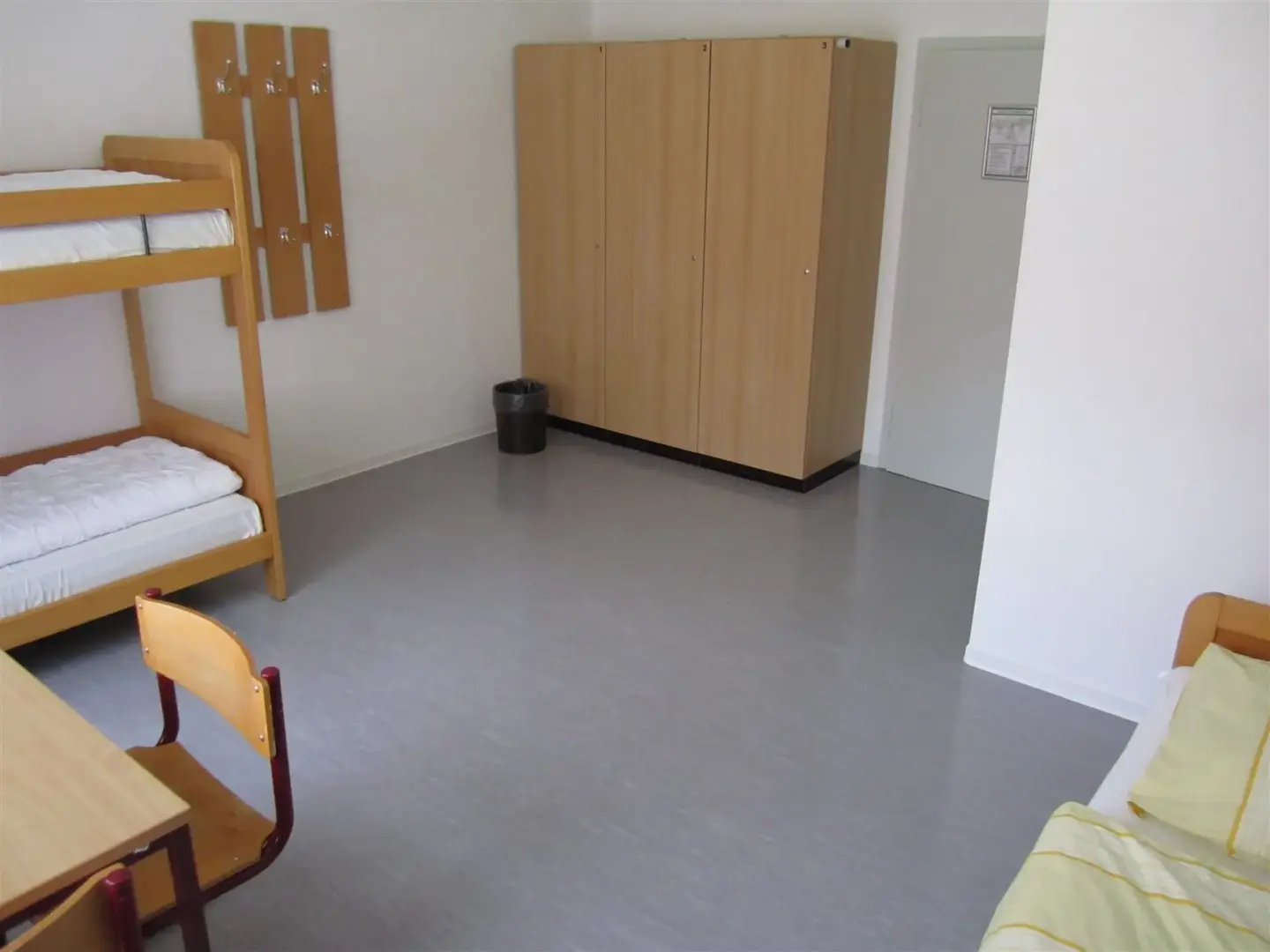 Klassenfahrt Darßer Boddenküste - großes Zimmer mit drei Betten, Schrank, Tisch und Stühlen