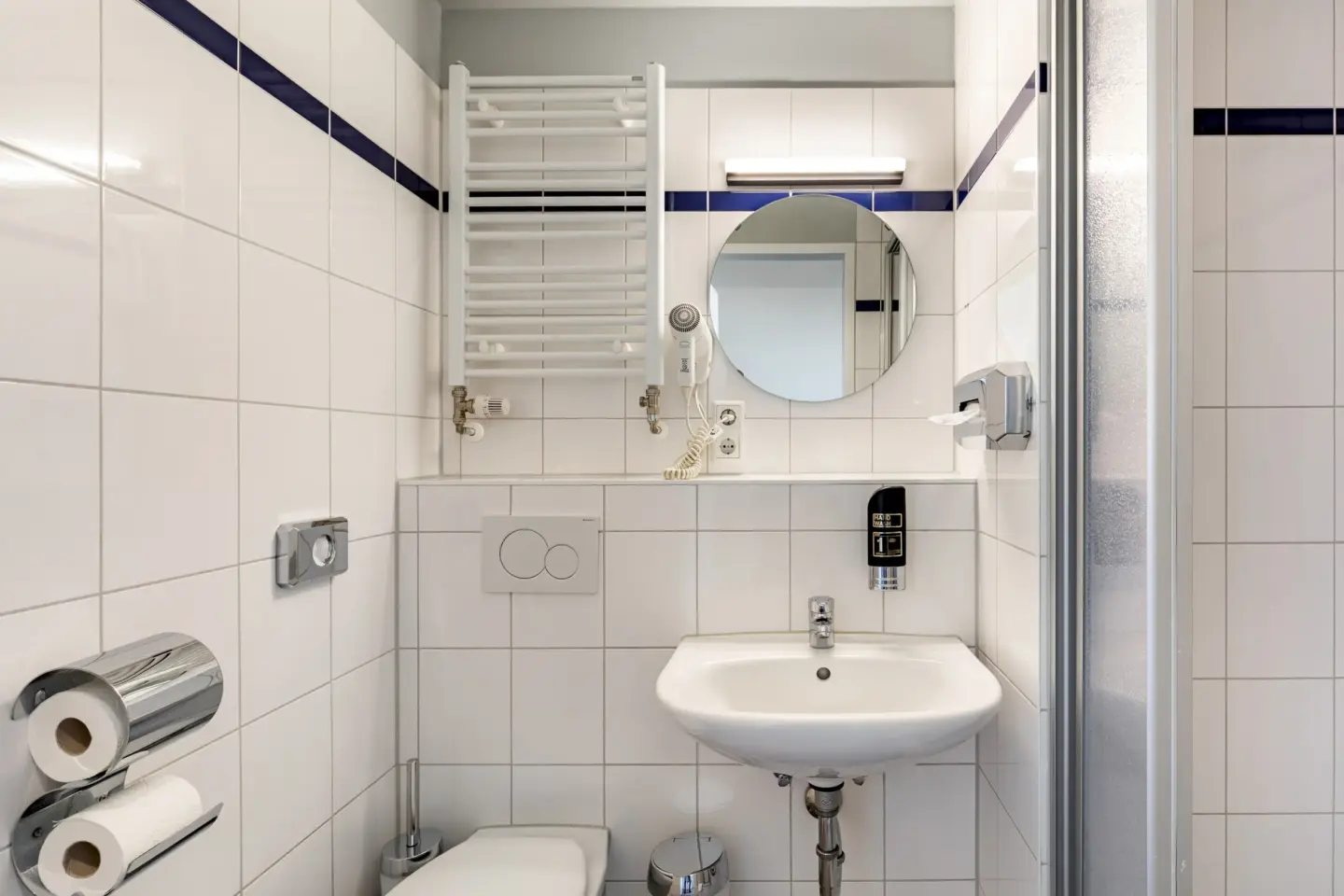 Klassenfahrt Aachen - helles Badezimmer mit WC, Waschbecken, Spiegel und Dusche