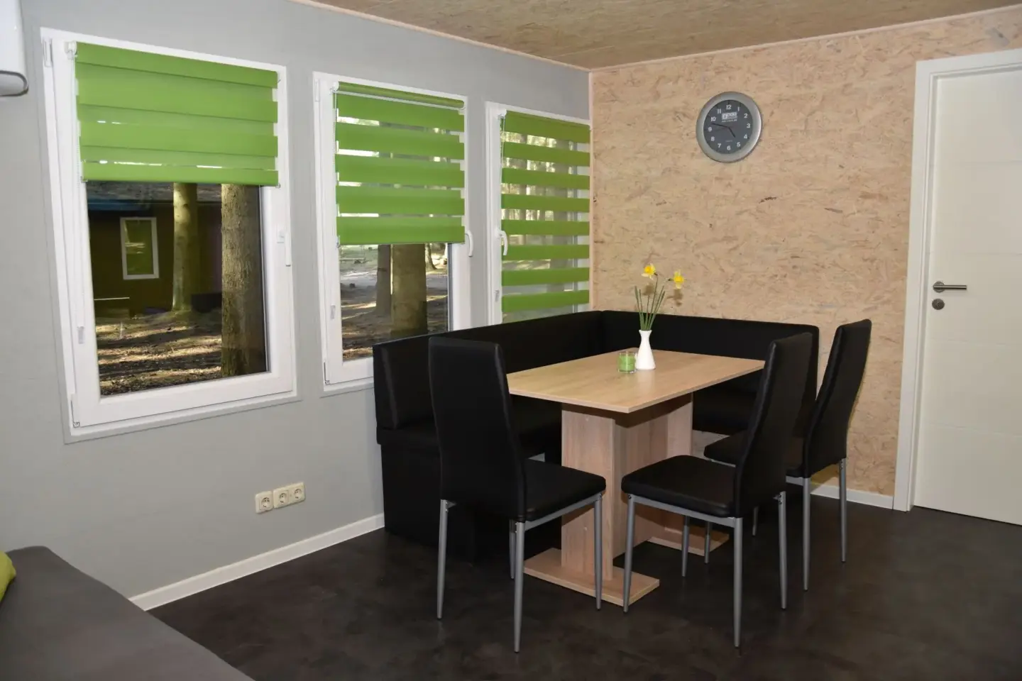 Klassenfahrt Dranske - Sitzecke mit Tisch und schwarzen Stühlen und drei Fenster