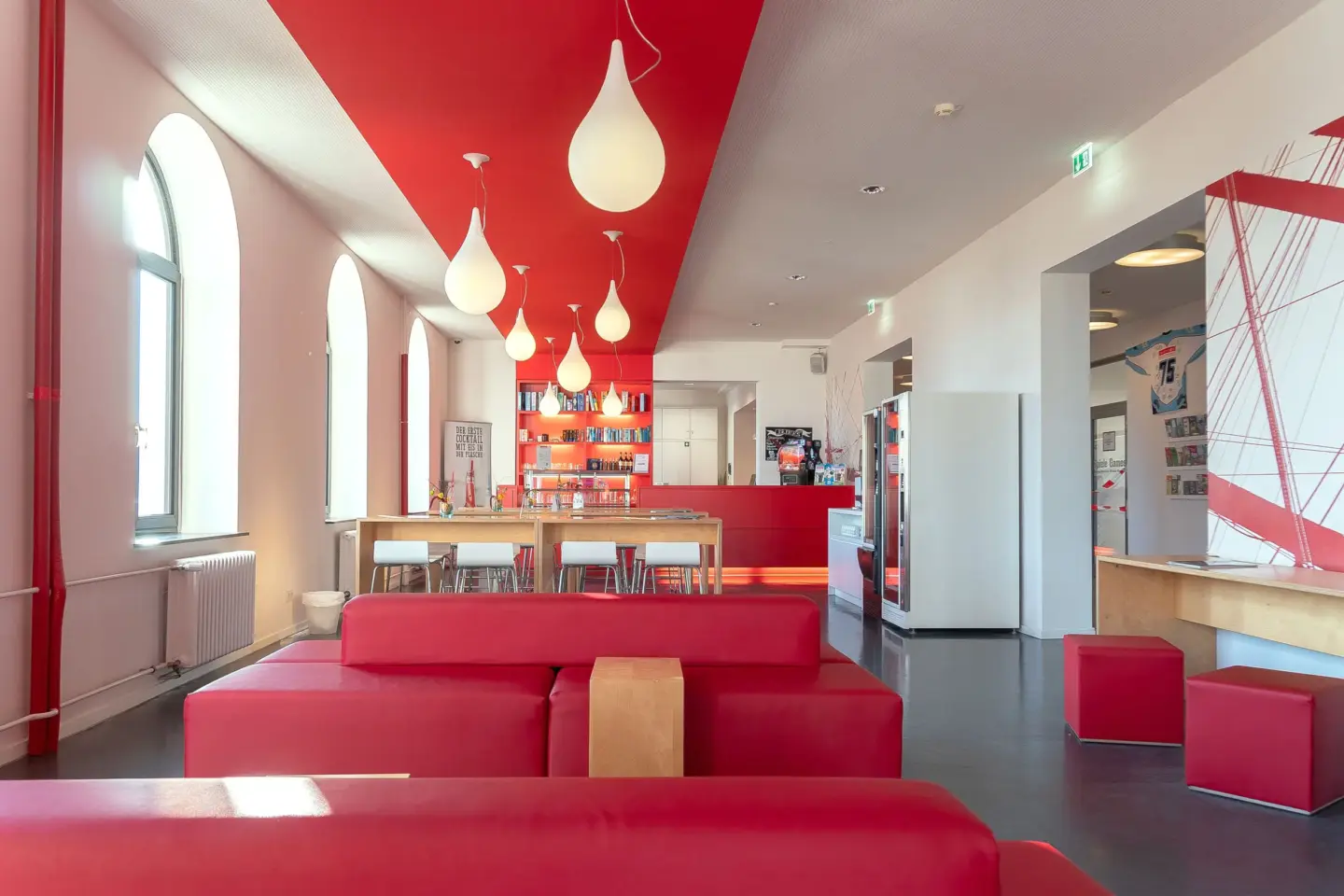 Klassenfahrt Bremerhaven - Aufenthaltsraum mit rotem Sofa, dahinter Tische und Stühle