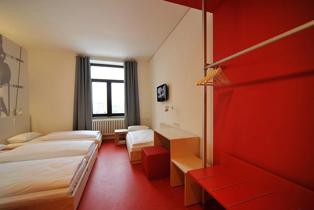 Klassenfahrt Bremerhaven - Zimmer mit vier Einzelbetten, rotem Fußboden und roter Wand