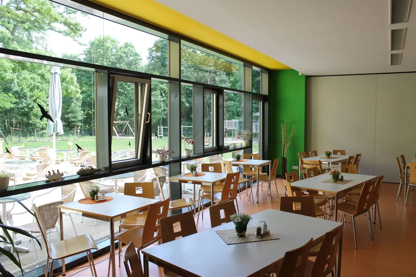 Klassenfahrt Dessau - Speisesaal mit Tischen und Stühlen und Blick in den Garten