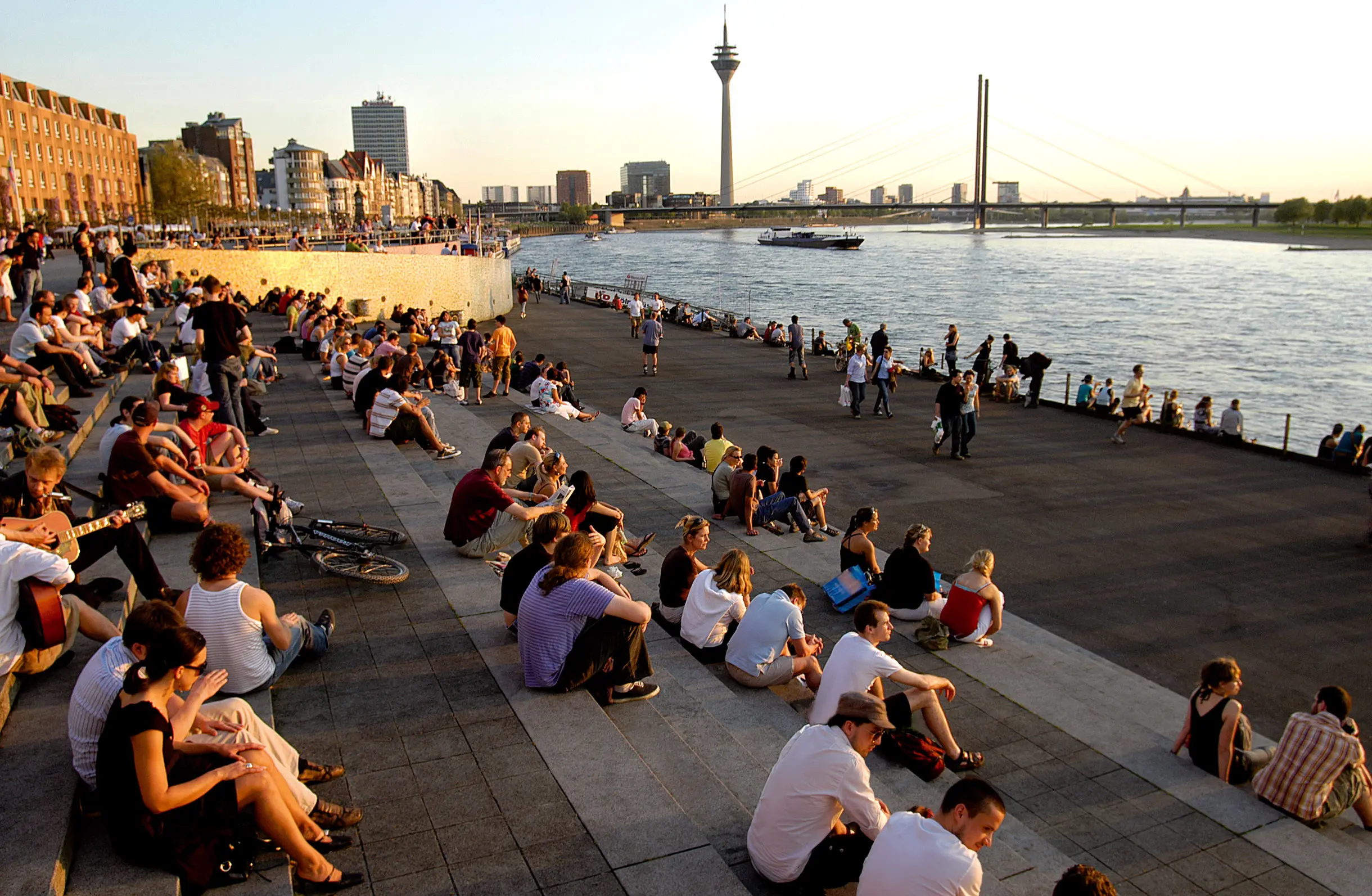 Klassenfahrt Düsseldorf - Die Rheintreppe mit vielen verweilenden Menschen während des Sonnenuntergangs