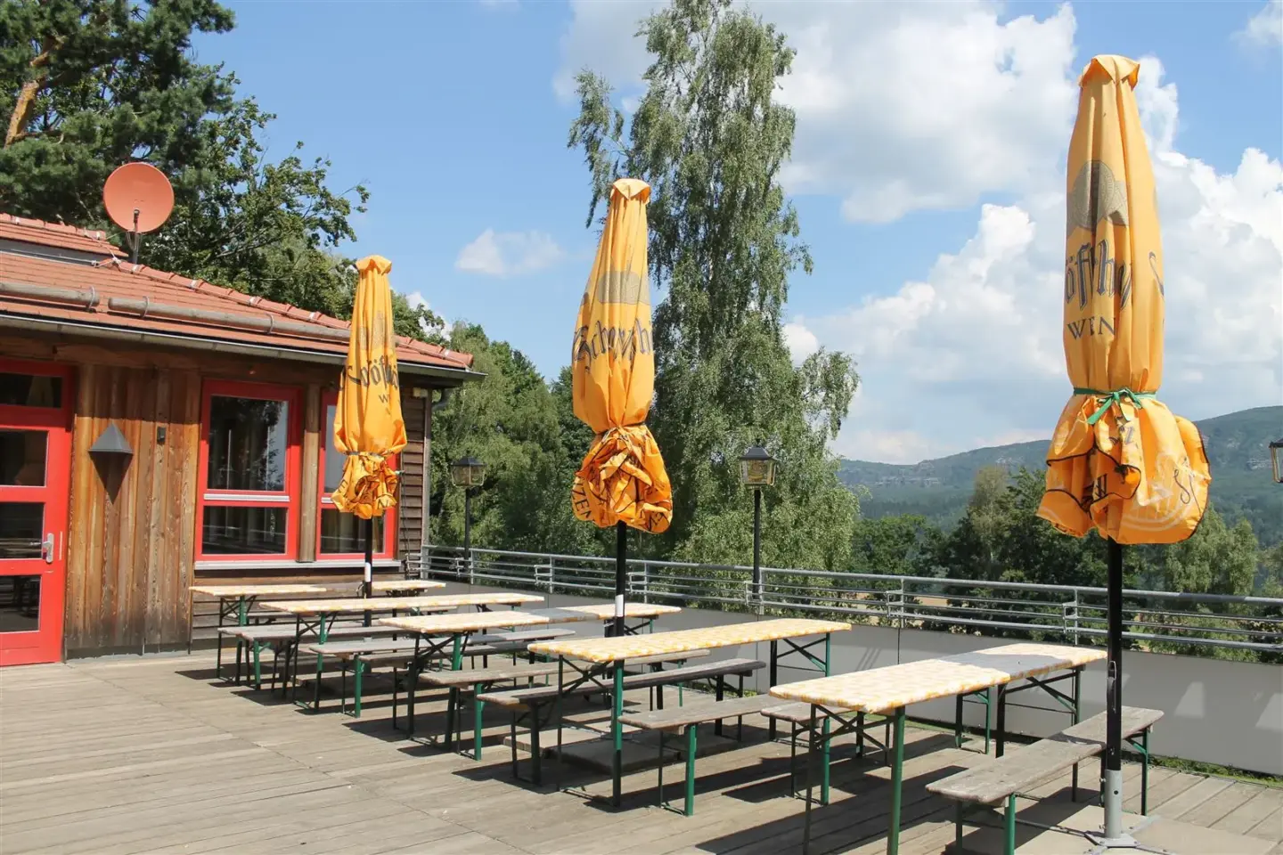 Klassenfahrt Sächsische Schweiz - Sitzbereich mit Biertischen und Bänken und großen Sonnenschirmen