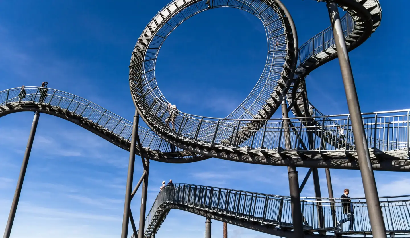Klassenfahrt Duisburg - Das wie eine Achterbahn anmutende, begehbare Kunstwerk Tiger & Turtle vor blauen Himmel.